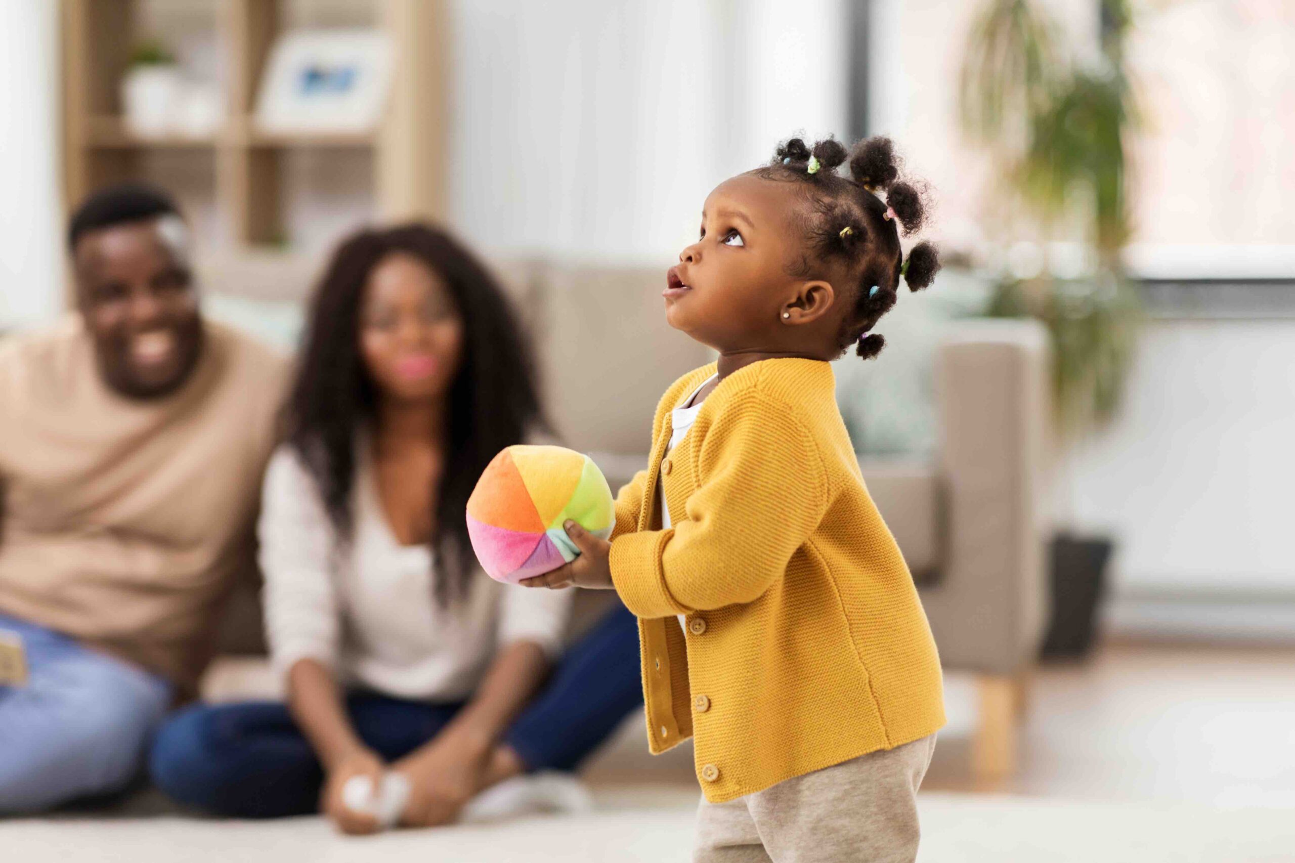 African American baby girl playing with ball at home.